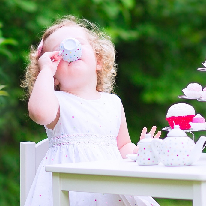 Little girl drinking from her toy tea set