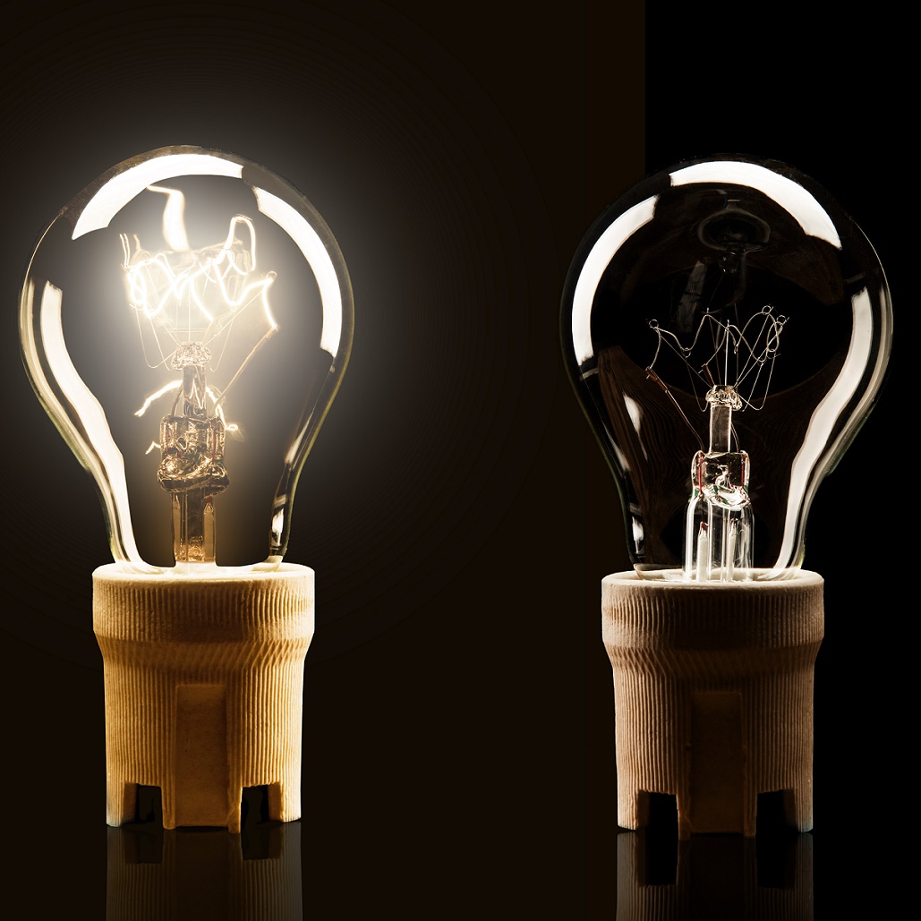 two light bulbs against a black background, one turned on and one turned off