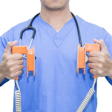 Close-up of person in scrubs holding defibrillator