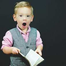 Young boy holding book and looking shocked