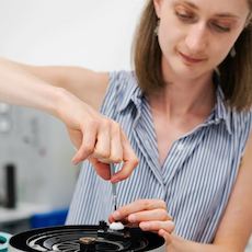 Female engineer adjusting noise filter with a fine screwdriver