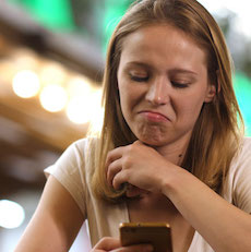 Young woman looks sceptically at her phone