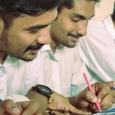 Men writing with pens or phones, smiling